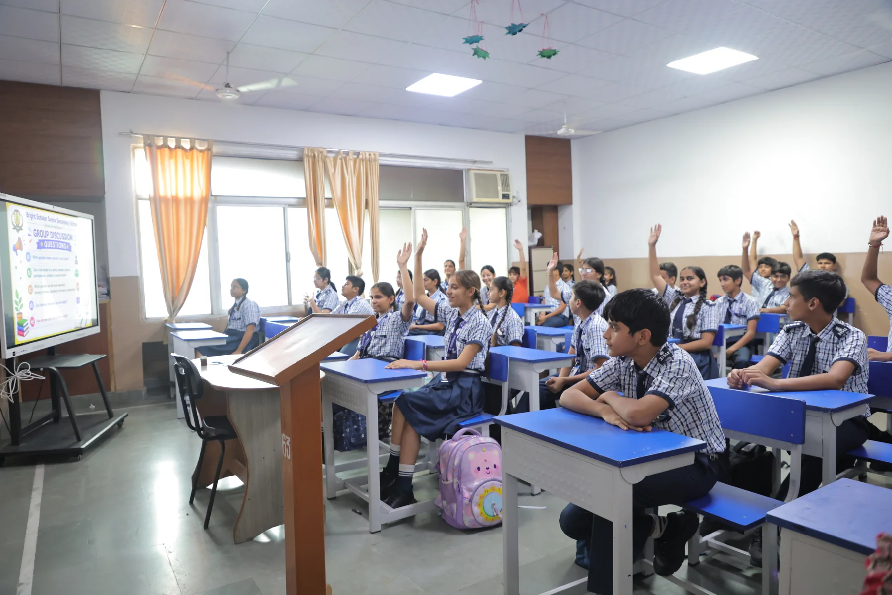 A classroom of hands raised to answer a question