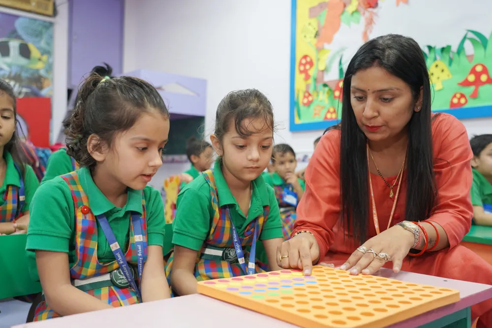 A teacher working with young students at a classroom table