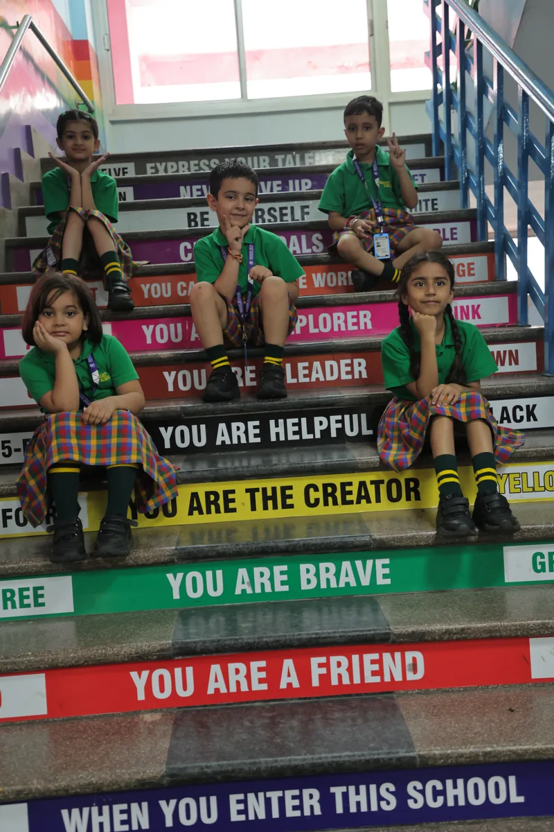 Pre-primary children seated on the staircase whose risers read “you are a leader, you are brave, you are a friend”