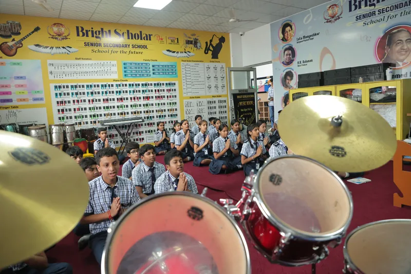 The music room, drum kit in the foreground and the class seated on the red carpet