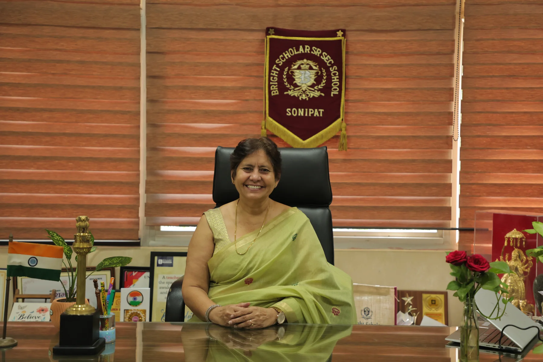 Dr Kiran Dalal, Principal, at her desk under the school pennant
